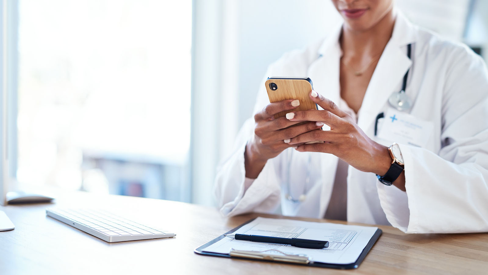 Shot of a young doctor using a smartphone in her consulting room
