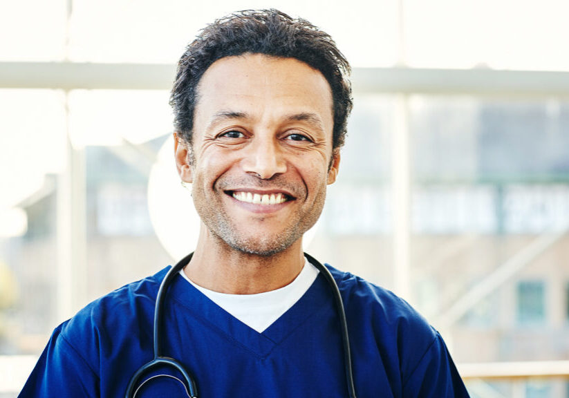 Portrait of successful male surgeon with stethoscope around his neck and smiling in hospital