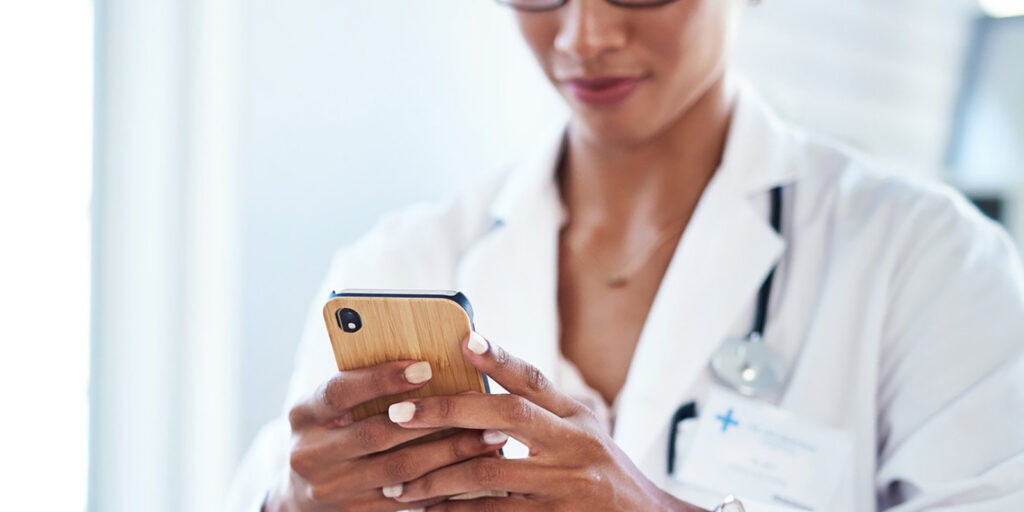 Shot of a young doctor using a smartphone in her consulting room